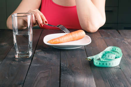 displeased woman keeping a strict diet and eating vegetablesの写真素材