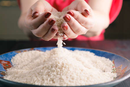 Two hands with rice grains over plateの写真素材