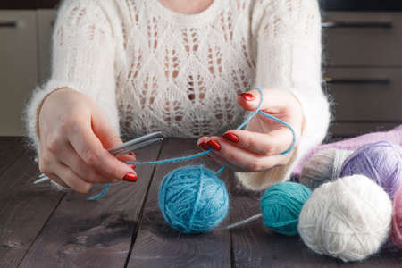 woman is knitting on a kitchen tableの写真素材
