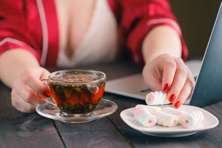woman working on computer at home at night with tea cupの写真素材