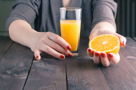 Closeup image of a woman hand holding glass of orange juiceの写真素材