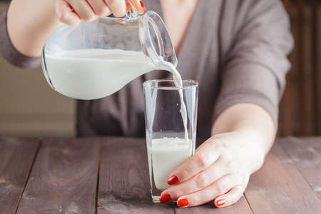 woman pour out milk into glassの写真素材