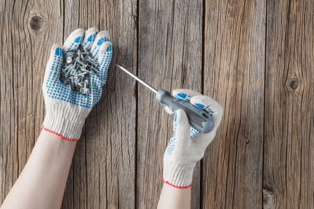 Hand of the worker screws in a wooden block with a screwdriver