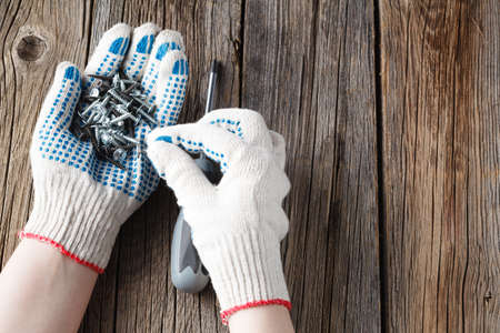 Hand of the worker screws in a wooden block with a screwdriver