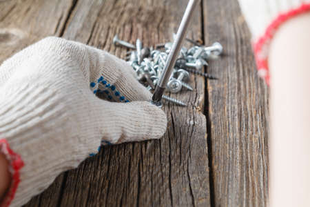 Hand of the worker screws in a wooden block with a screwdriverの写真素材
