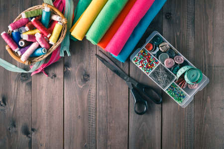Sewing kit. Scissors, bobbins with thread, buttons and needles on rustic wooden tableの写真素材