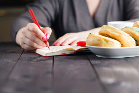 Women write love message. Breakfast with coffee and donutsの写真素材