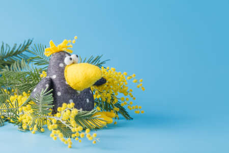 Kid toy crow with spring flowers on blue backgroundの写真素材