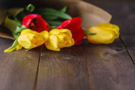 Tulip bouquet in craft paper on wooden tableの写真素材