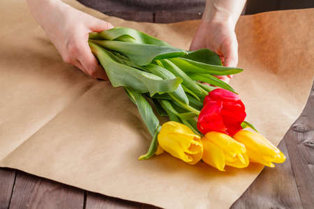 Woman makind bouquet of tulips in craft paperの写真素材