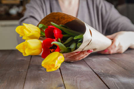 Woman holding in hands tulips in craft paperの写真素材