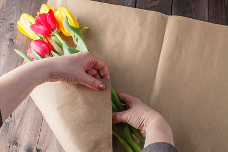 Woman makind bouquet of tulips in craft paperの写真素材