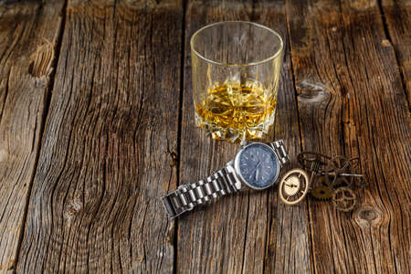 Whiskey and clock gears on wooden tableの写真素材