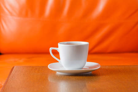 cup of tea on wood table with orange background