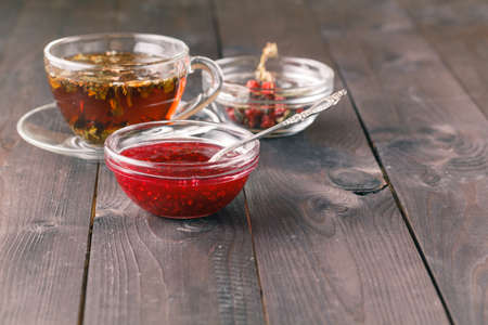 cup of tea on wooden table over wooden background with raspberry jamの写真素材
