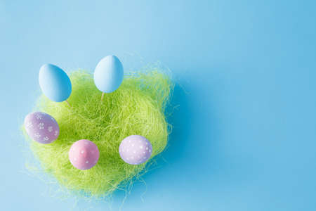 Springtime nest with colorful Easter Eggs against blue backgroundの写真素材