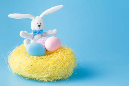 Homemade Hand Painted Easter Eggs of Various Colors in a Nest on blue Background
