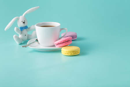 Colored french macaroon and coffee cup on aquamarine with toy rabbitの写真素材