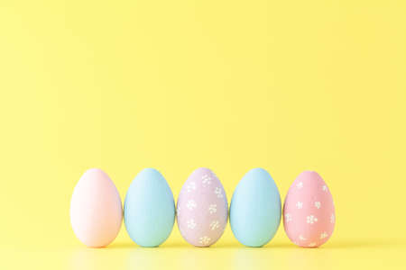 Easter eggs painted in pastel colors on yellow paper background. Easter conceptの写真素材
