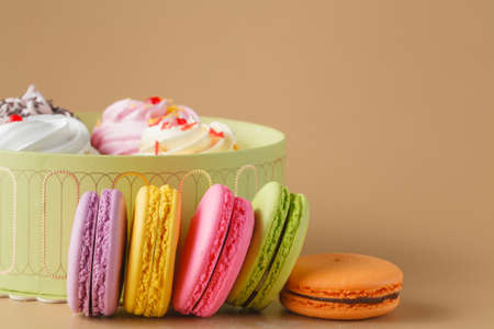 Gift Box of cupcakes and Colourful Macaron on beige Background, Free Space for Textの写真素材