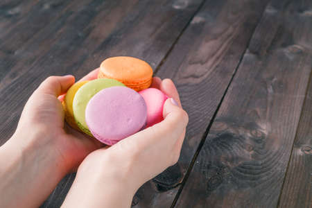 Women's hands holding macaroons on rustic tableの写真素材