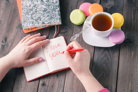 Woman write letter i love you while drinking coffee