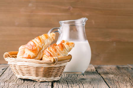 Fresh homemade croissants on a wooden table in the rustic kitchenの写真素材