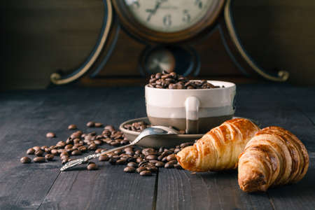 Fresh coffee beans on wood with croissantの写真素材