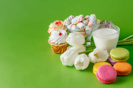 Spring breakfast with white tulips and sweets, macaroons and cupcakesの写真素材