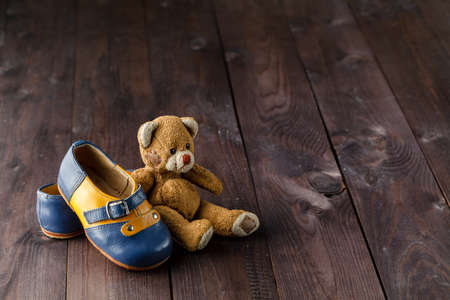 Baby boots on wooden table over wall grunge background, vintage style