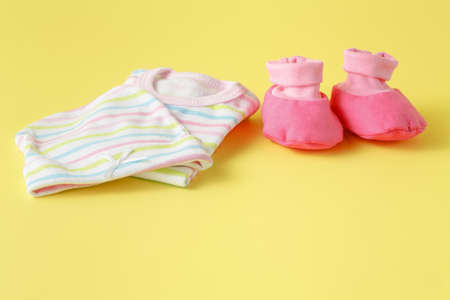 Pink baby shoes on yellow background