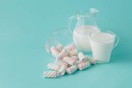 Twisted marshmallow on plain aquamarine background with milkの写真素材