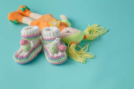 Baby shoes and doll on plain background