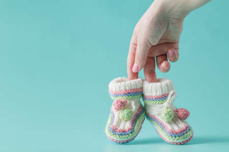 female hand holds small baby shoesの写真素材