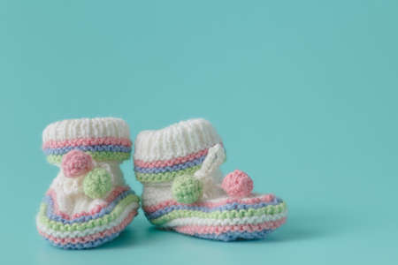Newborn announcement. knitted baby booties on plain aquamarine background