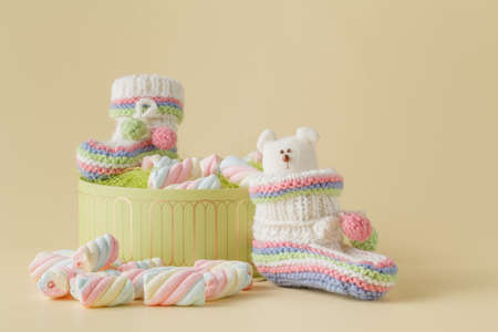 Newborn announcement concept. Knitted booties on beige background with sweetsの写真素材