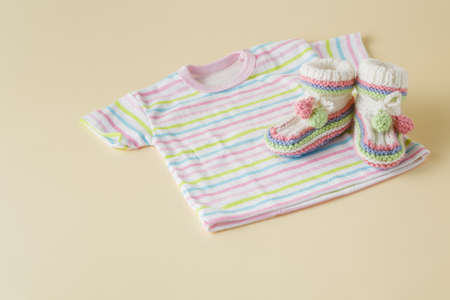 newborn baby clothes and shoes on beige backgroundの写真素材