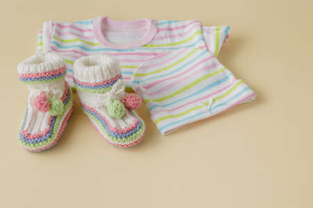 newborn baby clothes on beige plain backgroundの写真素材
