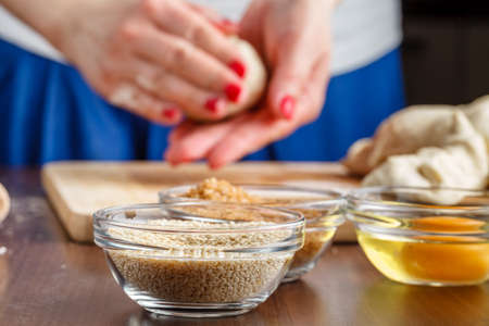 Female hands kneading dough on wooden tableの写真素材