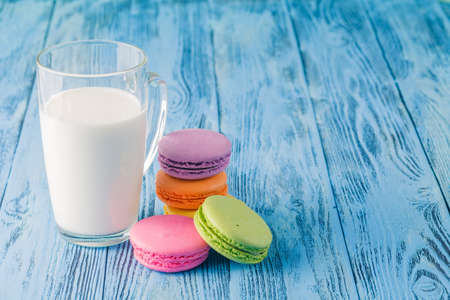 Glass of milk with french macaroon on blue tableの写真素材