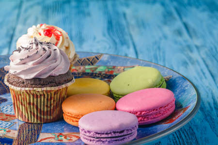 Few tasty cupcakes with macaroons on plateの写真素材
