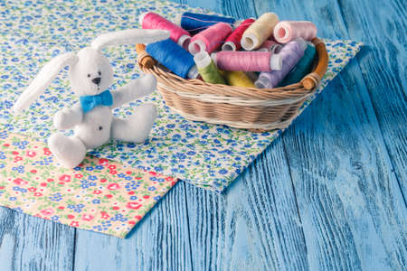 threads in basket and soft toy on blue table