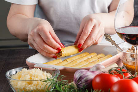 Woman making cannelloni or lasagne on kitchenの写真素材