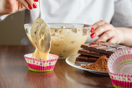 Woman prepare muffins on kitchen table by handsの写真素材