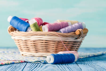 threads in basket and soft toy on blue tableの写真素材