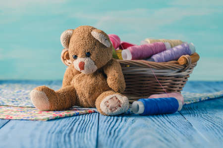threads in basket and soft toy on blue table