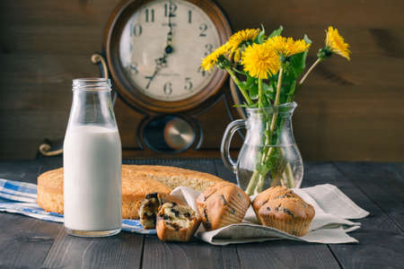 Summer breakfast with muffins, milk and dandelion flowers on tableの写真素材