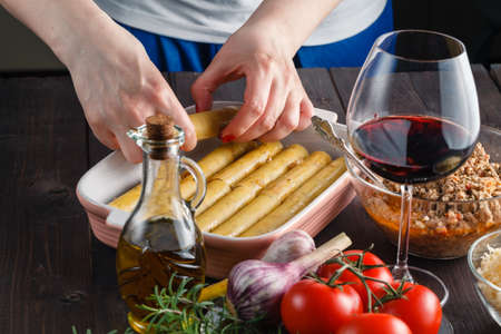 Woman making cannelloni or lasagne on kitchenの写真素材