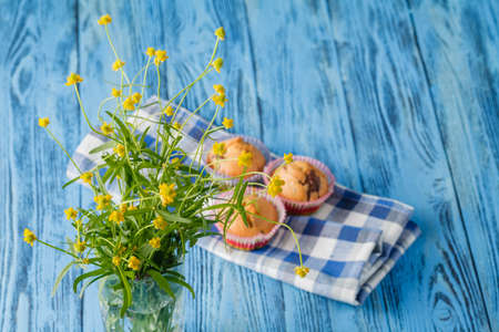 Blueberry muffins on table with toy and flowersの写真素材