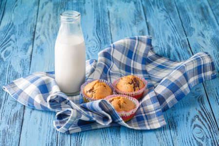 Breakfast with muffins and milk. Blue napkin on wooden tableの写真素材